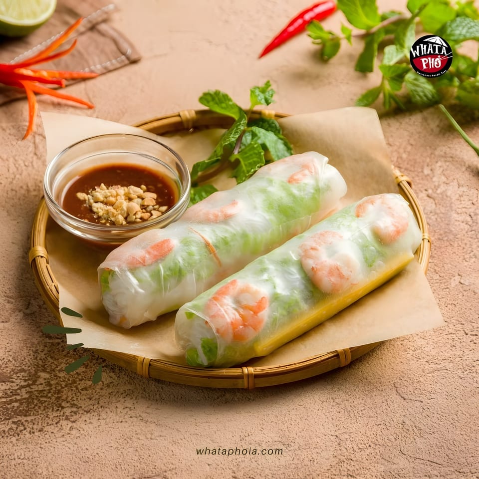 Two fresh shrimp spring rolls with peanut dipping sauce, mint, and chili on a bamboo tray.