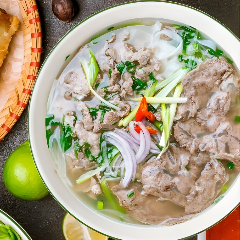A close-up of a bowl of Whata Pho's beef pho, garnished with fresh herbs and chili.