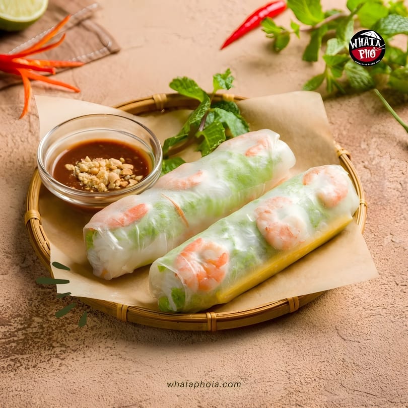 Two fresh Whata Pho spring rolls with shrimp and vegetables, served with peanut sauce.